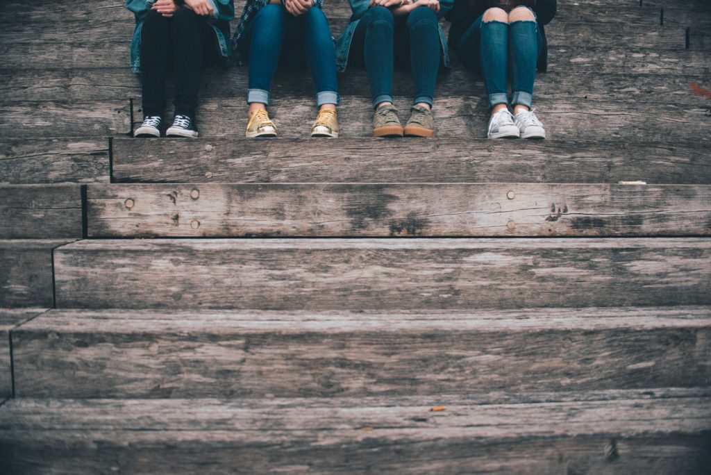 four people's legs and shoes on wooden steps